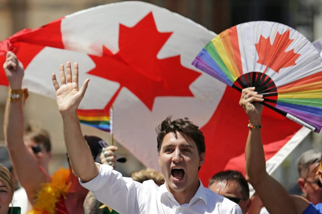 man shouting and raising his hand with the canadian flag in the background