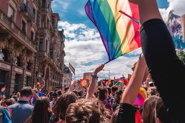 people marching and a lgbt flag being waved