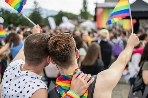 two men holding a lgbt flag